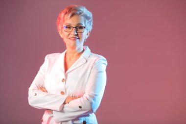 güzel şık kadın yaşlı, gözlük giyiyor, beyaz bir ceket pembe bir arka planda