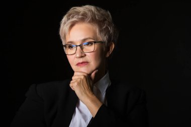 siyah bir arka plan üzerinde gözlük şık yaşlı yaşlı kadın ciddi bir yüz ile uzak görünüyor