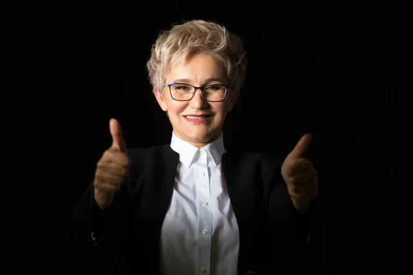 stylish elderly woman in glasses and black jacket on a black background