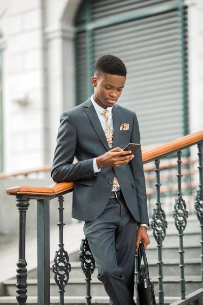 handsome young african man in a suit with a phone in his hand