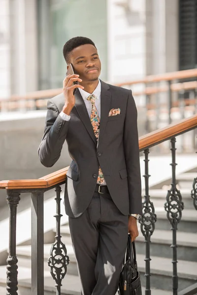 handsome young african man in a suit talking on the phone