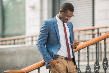 elinde bir telefon ile takım elbiseli yakışıklı genç afrikalı adam