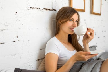 kapaklar altında yatakta oturan güzel genç kadın