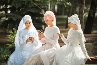 ellerinde telefonları ile şenlikli Müslüman elbiseler üç güzel genç kadın