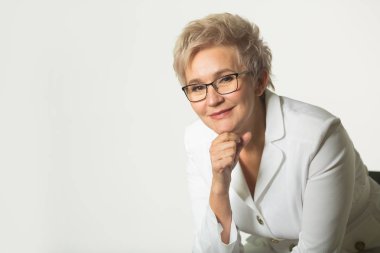 beyaz bir arka plan üzerinde beyaz bir ceket gözlük giyen kısa bir saç kesimi ile yetişkin bir kadının portresi