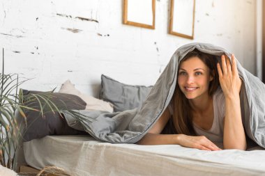 güzel genç kadın bir battaniye altında yatakta yatıyor