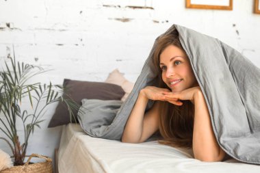 güzel genç kadın bir battaniye altında yatakta yatıyor