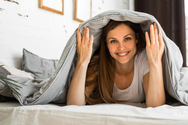 güzel genç kadın bir battaniye altında yatakta yatıyor