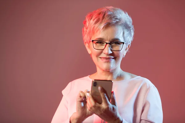 stylish elderly woman in glasses with a phone in her hand