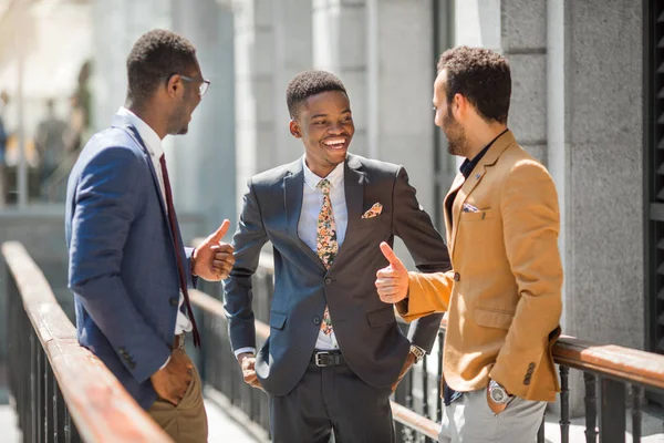 three handsome adult men in suits communicate