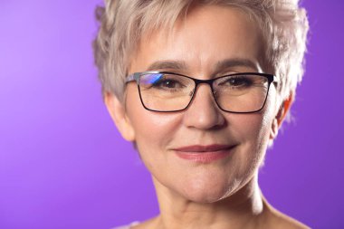 mor arka plan üzerinde kısa saç kesimi ile gözlük yetişkin kadın portresi