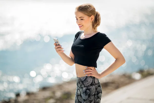 beautiful young woman jogging outdoors with a phone in her hand