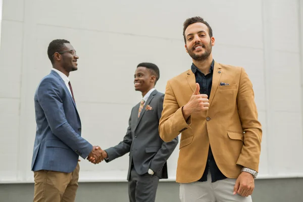 three young men in suits on a gray background