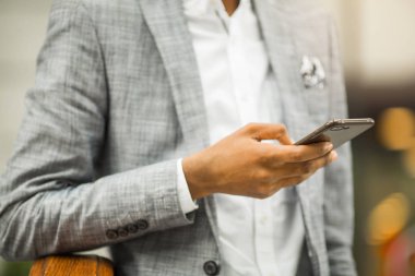 takım elbiseli Afrikalı adam elinde akıllı telefon