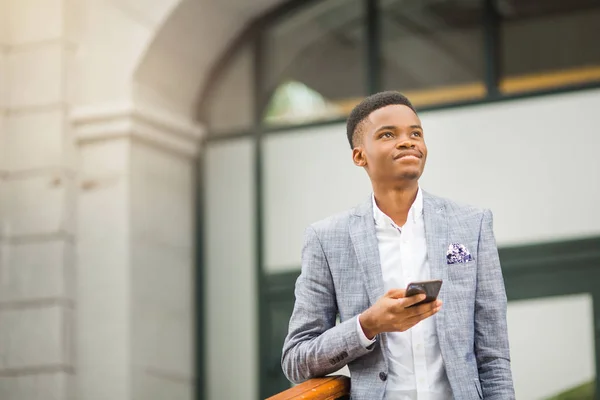 handsome young african man in a suit with a phone in his hand