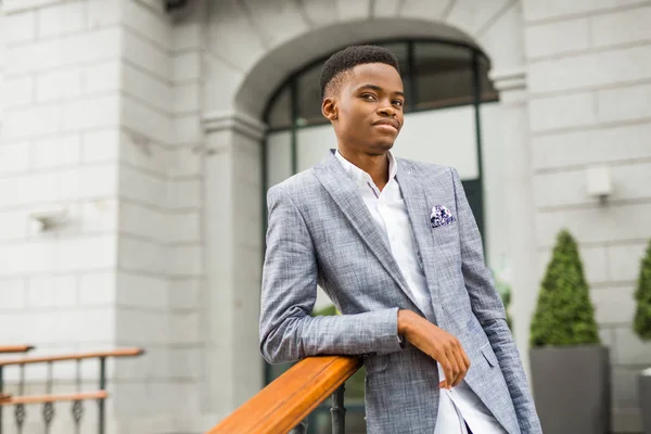 handsome young african man in suit near building