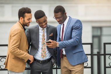 binanın yakınında takım elbiseli üç yakışıklı genç erkek telefonbakmak