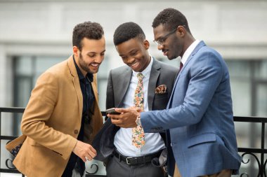binanın yakınında takım elbiseli üç yakışıklı genç erkek telefonbakmak