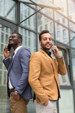 takım elbiseli iki yakışıklı genç adam telefonla arıyor