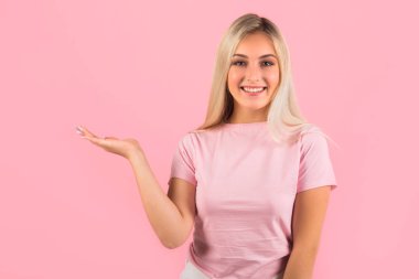 Pembe arka planda el hareketleriyle güzel genç bir kadın.