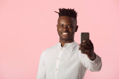  Yakışıklı Afrikalı adam pembe arka planda telefon ediyor.
