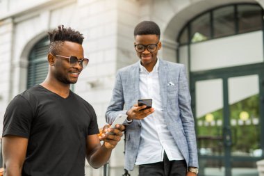 Ellerinde telefonlar olan genç Afrikalı adamlar.
