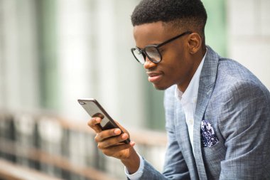 elinde bir telefon ile takım elbiseli yakışıklı genç afrikalı adam