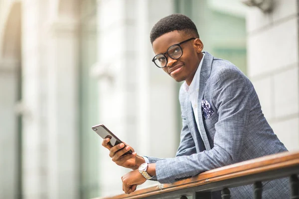 handsome young african man in a suit with a phone in his hand