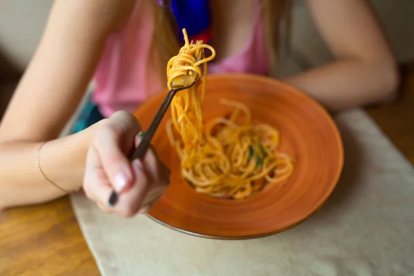 woman eating spaghetti from a plate in a restaurant