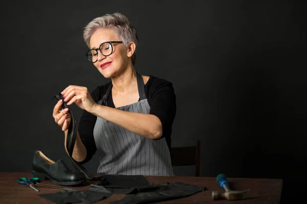 portrait of an adult woman with glasses and an apron on a black background at work