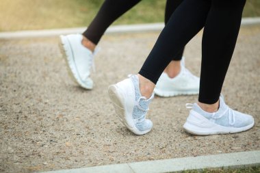 Yazın beyaz spor ayakkabılı bir kadının bacakları yolda.