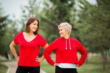 İki güzel yetişkin kadın yaz parkında spor yapıyor.