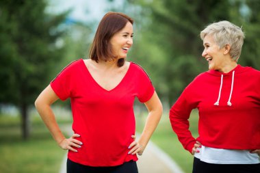 İki güzel yetişkin kadın yaz parkında spor yapıyor.