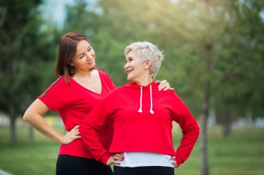 İki güzel yetişkin kadın yaz parkında spor yapıyor.