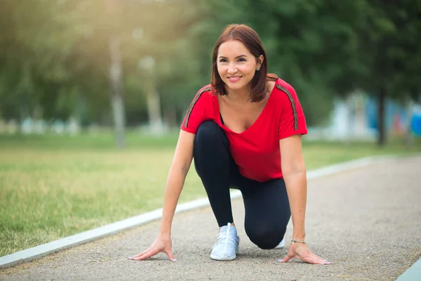 beautiful adult woman goes in for sports in the summer park