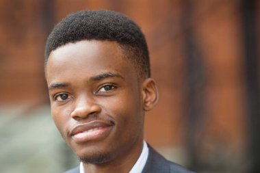 Tuğla duvara karşı takım elbiseli yakışıklı bir gencin portresi.