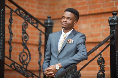 Tuğla duvara karşı takım elbiseli yakışıklı bir gencin portresi.