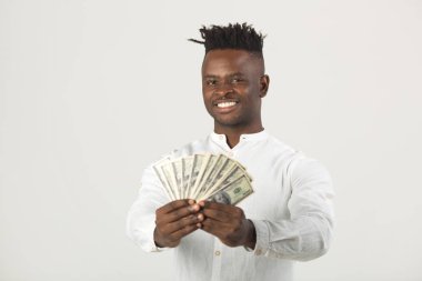 Beyaz tişörtlü yakışıklı Afrikalı bir adam ellerinde dolarlarla beyaz bir arka planda