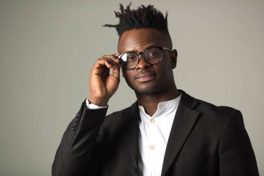 Siyah takım elbiseli yakışıklı Afrikalı genç adam gözlük takıyor.