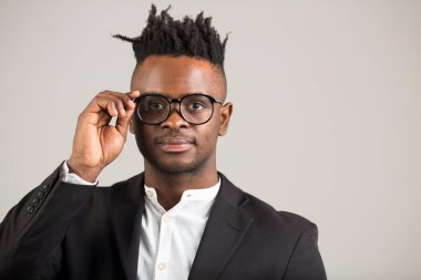 Siyah takım elbiseli yakışıklı Afrikalı genç adam gözlük takıyor.