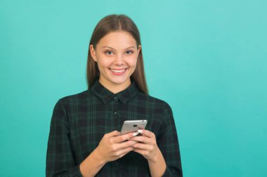 Yeşil arka planda yeşil tişörtlü güzel bir kadın. Elinde telefon var.