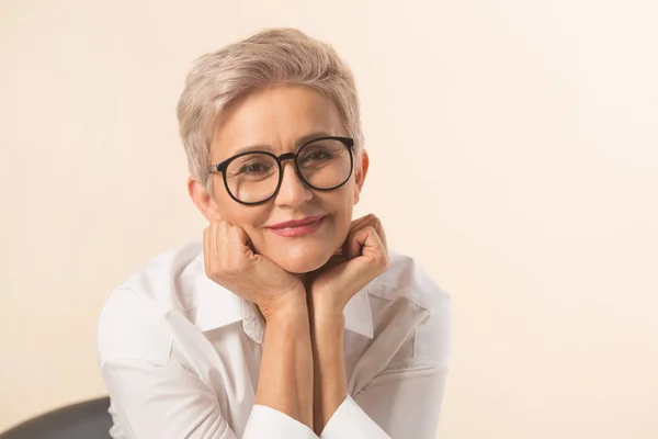 stylish beautiful woman with a short haircut, in a white shirt on a beige background