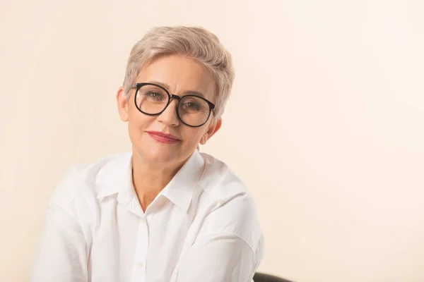 stylish beautiful woman with a short haircut, in a white shirt on a beige background