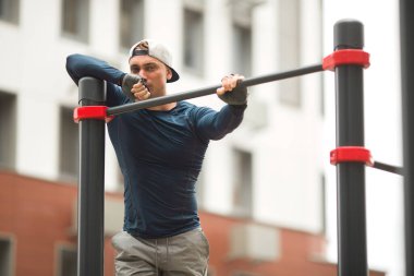 Spor giyimli yakışıklı genç adam dışarıda antrenman yapıyor.