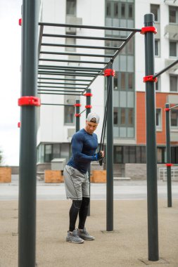 Spor giyimli yakışıklı genç adam dışarıda antrenman yapıyor.