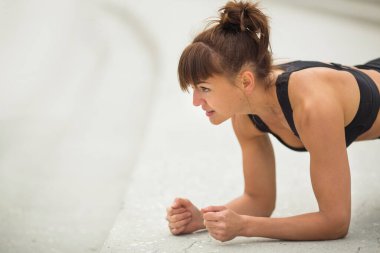 Spor figürlü güzel genç bir kadın açık havada antrenman yapıyor.