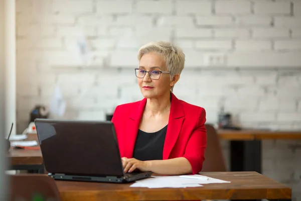 Piękna Starsza Kobieta Czerwonej Kurtce Pracuje Biurze Laptopem — Zdjęcie stockowe
