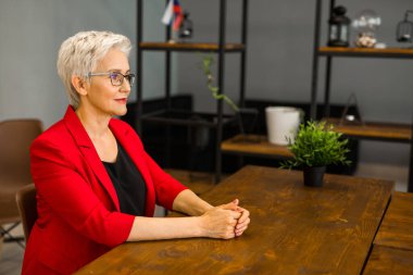 Kırmızı ceketli, şık, yaşlı bir kadın.