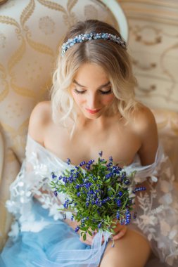  Güzel, genç bir kadın. Makyajlı ve saç stili olan. Bir buket çiçekli, narin bir pijamada.