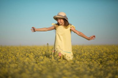 Gökyüzüne karşı sarı bir tarlada şapkalı güzel bir genç kızın portresi.